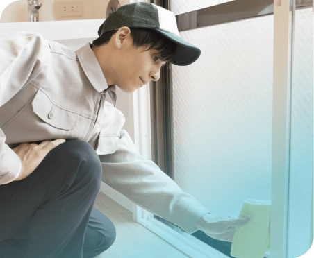 窓の溝をスポンジで掃除する男性