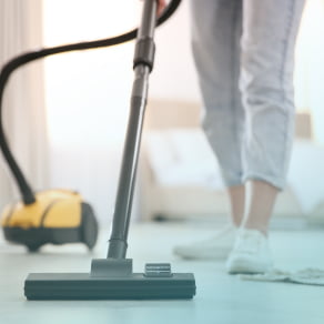 部屋で掃除機をかける女性